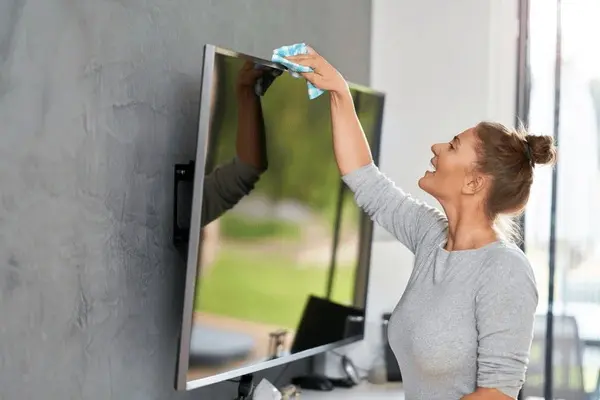 Bild Junge Frau beim Reinigen des Fernsehers